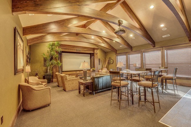 A large living room with a projector screen and tables and chairs