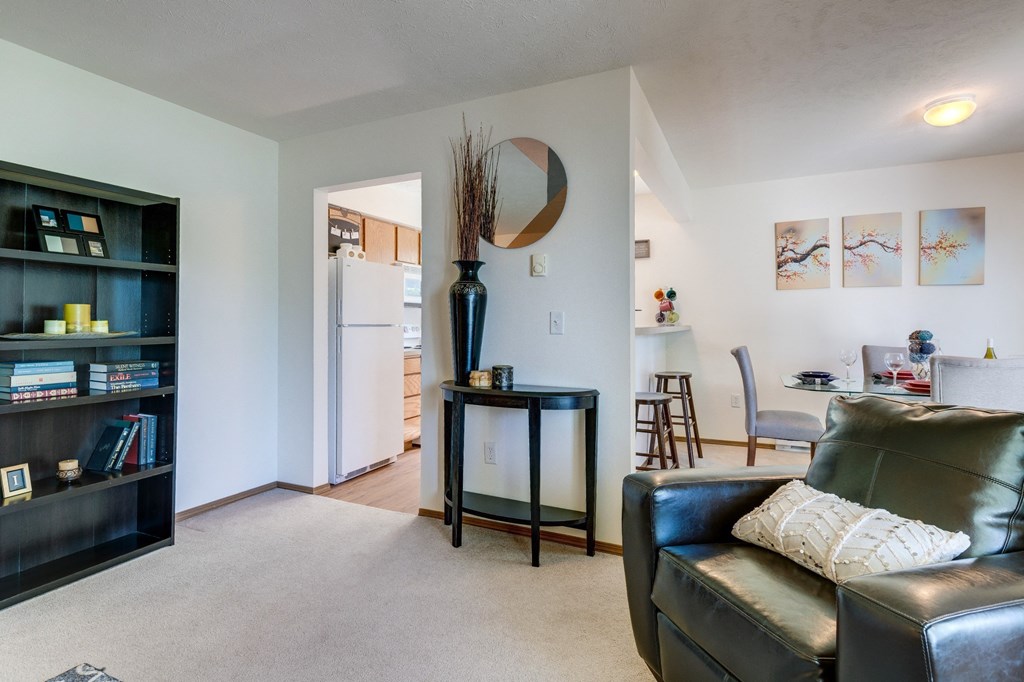 a living room with a couch and a chair and a kitchen with a table