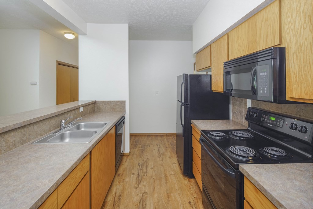 a kitchen with a black stove top oven next to a sink and a refrigerator