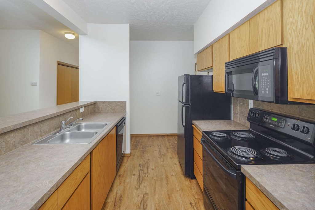 a kitchen with a black stove top oven next to a sink and a refrigerator