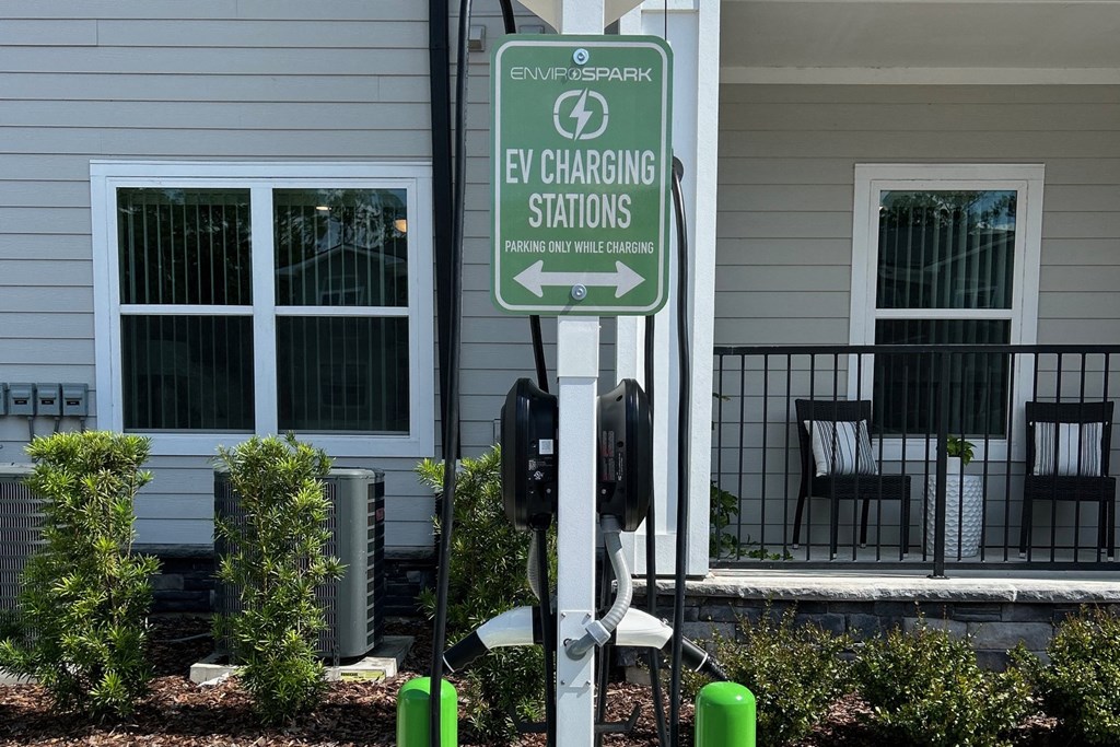 a green electric charging station sign in front of a house