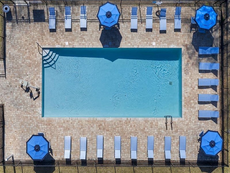 an aerial view of a swimming pool with blue umbrellas