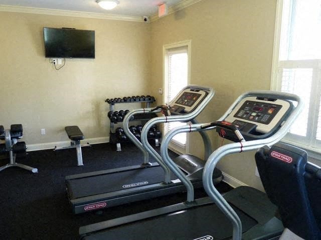 a workout room with a treadmill and a tv