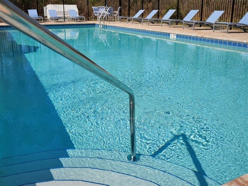 a large swimming pool with a railing and chairs in it