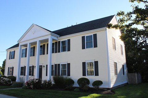 A white house with black shutters and a black roof.