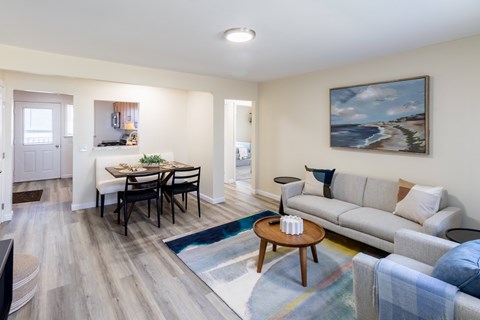 A living room with a grey couch, a coffee table, and a painting on the wall.