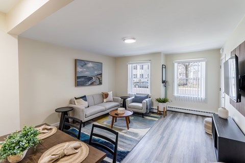 A living room with a couch, chairs, and a table with a plant on it.