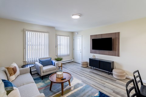 A living room with a grey couch, a coffee table, and a flat screen TV mounted on the wall.