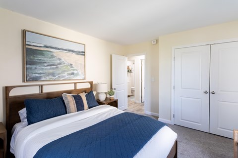 A bedroom with a large bed and a painting on the wall.