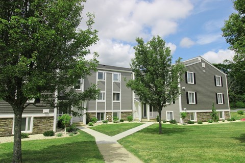 an apartment complex with trees and a sidewalk