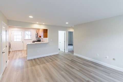 A spacious living room with a white counter and light wood flooring.