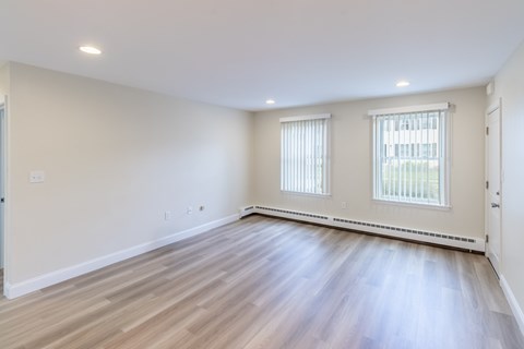 A room with wooden floors and two windows.