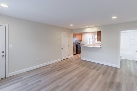 A spacious room with light wood flooring and white walls.