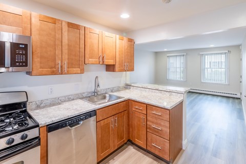 A kitchen with wooden cabinets and a stainless steel dishwasher.
