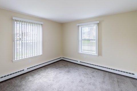 A room with two windows and a carpeted floor.