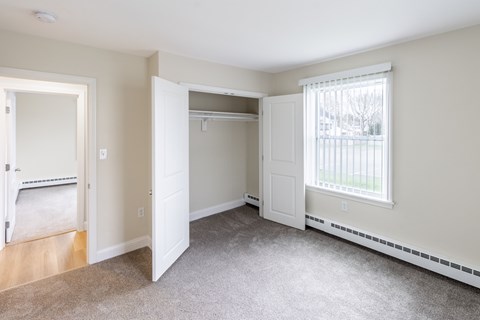 A room with a carpeted floor and a window with blinds.