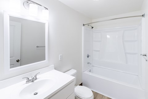 A white bathroom with a toilet, sink, and bathtub.