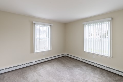 A room with two windows and a carpeted floor.