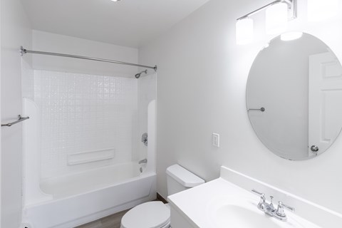 A white bathroom with a toilet, sink, and shower.