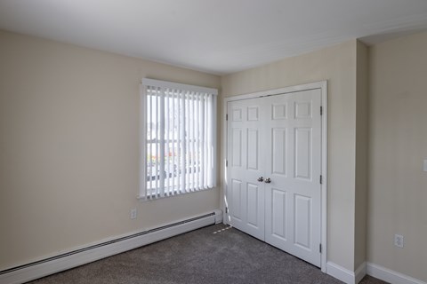 A room with a white door and a window with blinds.