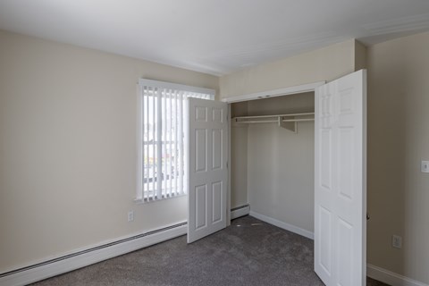 A room with a carpeted floor and a window with blinds.