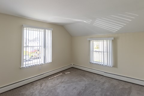 A room with two windows and carpeted floor.