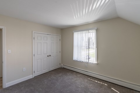 A room with a white door and a window with blinds.