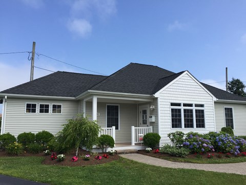 A house with a grey roof and white walls with a small porch.