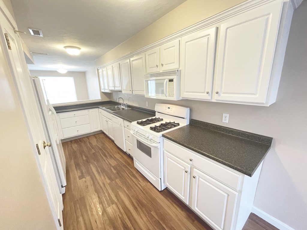 a kitchen with white cabinets and a stove and a microwave