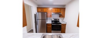 an empty kitchen with stainless steel appliances and wooden cabinets