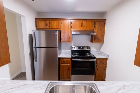 an empty kitchen with stainless steel appliances and wooden cabinets