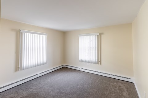 A room with two windows and carpeted floor.
