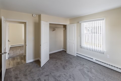 A room with a carpeted floor and a window with blinds.
