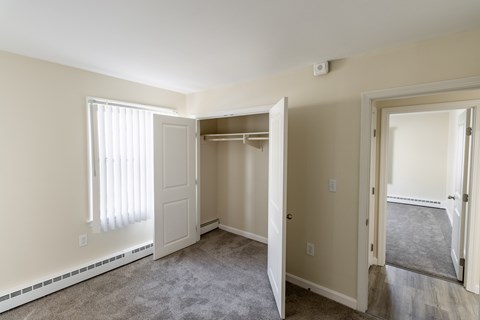 A room with a carpeted floor and a window with blinds.