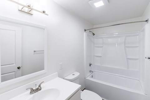 A white bathroom with a toilet, sink, and bathtub.