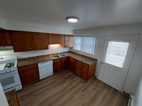 an empty kitchen with wood flooring and wooden cabinets