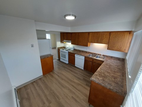 an empty kitchen with wooden cabinets and white appliances
