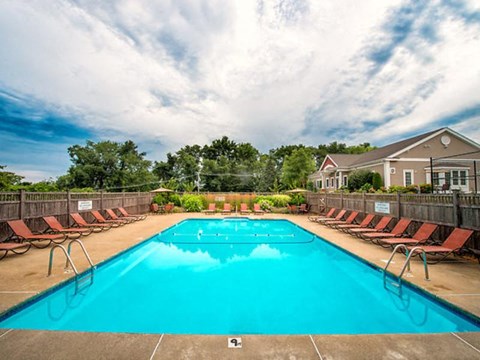 a swimming pool with chairs and a house in the background