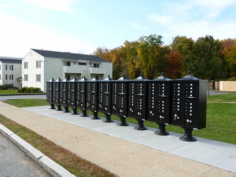 a line of mailboxes on a sidewalk in front of a house