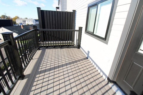 a balcony with a black railing and a white house