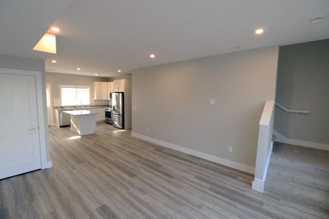 A room with a kitchen area in the background and a dining table in the foreground.