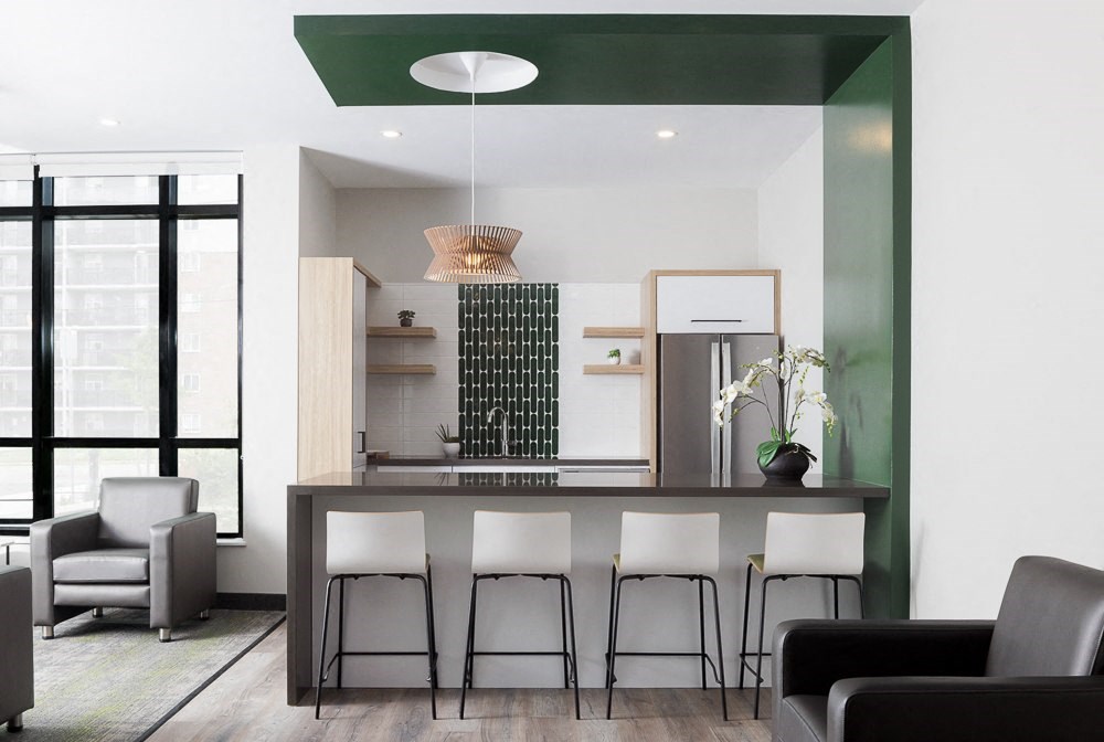 A modern kitchen with white and black furniture and a green accent wall.