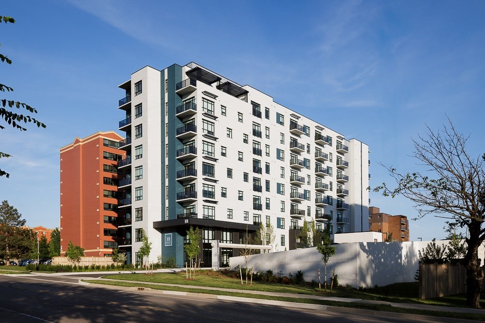 A modern multi-story apartment building with balconies and a mix of white and darker colored facades.