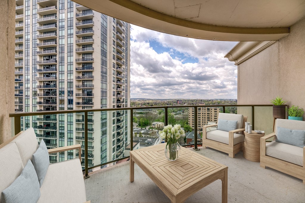 a balcony with two chairs a table and a vase of flowers