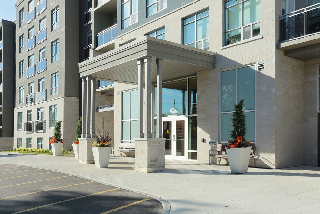 an entrance to an apartment building with potted plants on the sidewalk