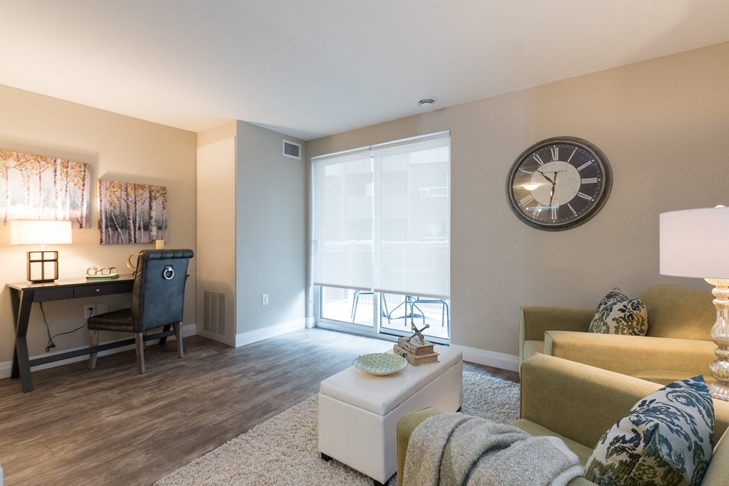 a living room with a large window and a desk with a chair