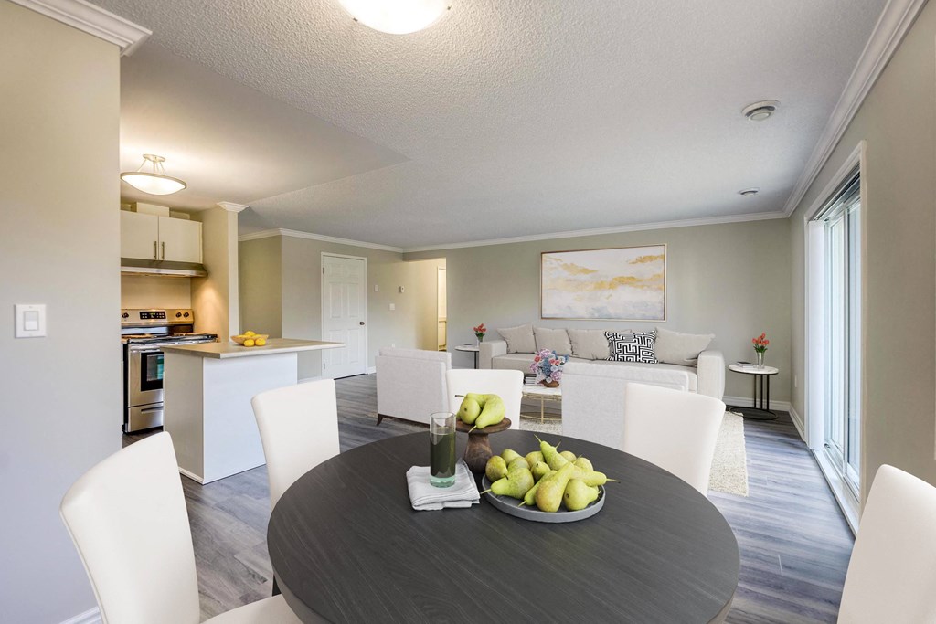 a dining area with a table and chairs and a kitchen in the background