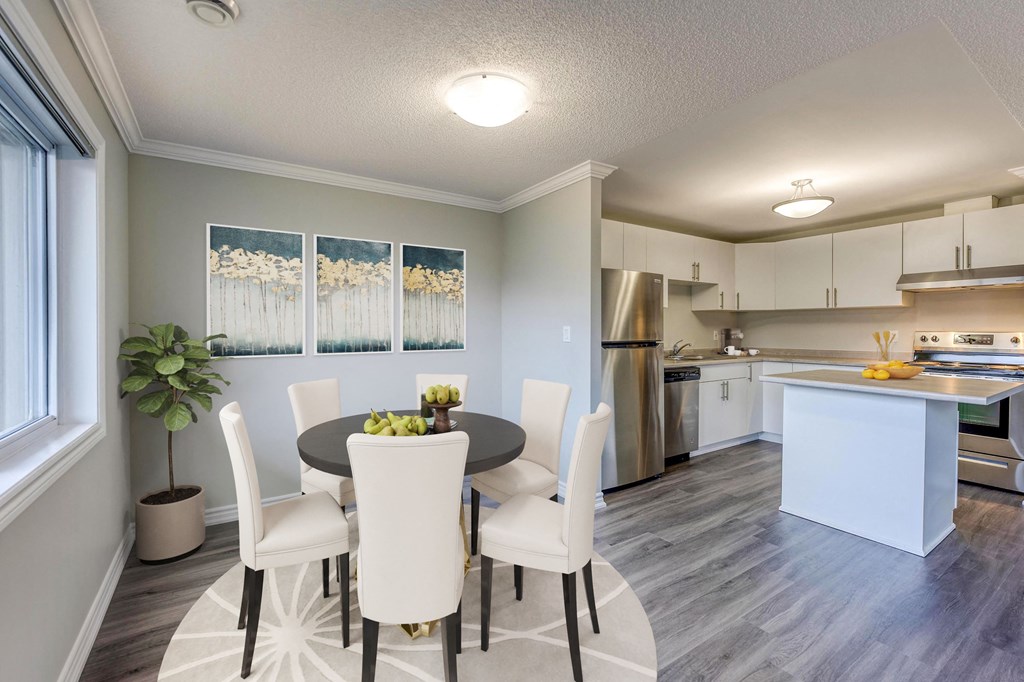 a dining area with a table and chairs and a kitchen in the background