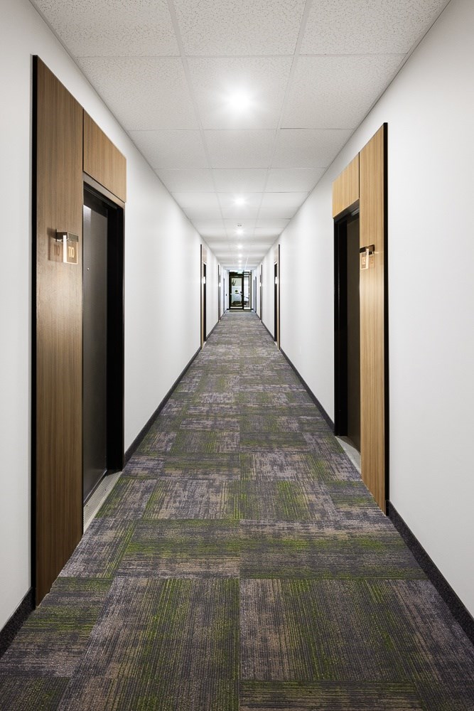 A long hallway with doors on both sides and a carpeted floor.
