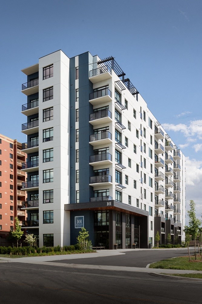 A modern apartment building with balconies on the upper floors.